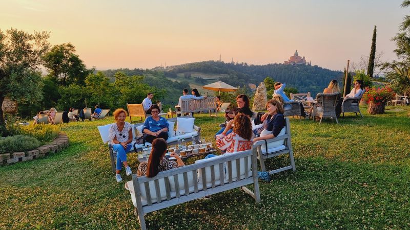 Ospiti sul prato de La Galeazza al tramonto, con vista sul Santuario di San Luca