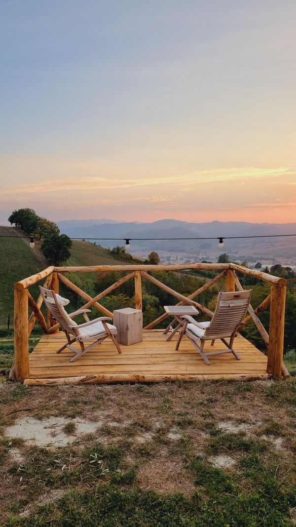 Terrazza in legno con due sdraio affacciata sui colli bolognesi al tramonto