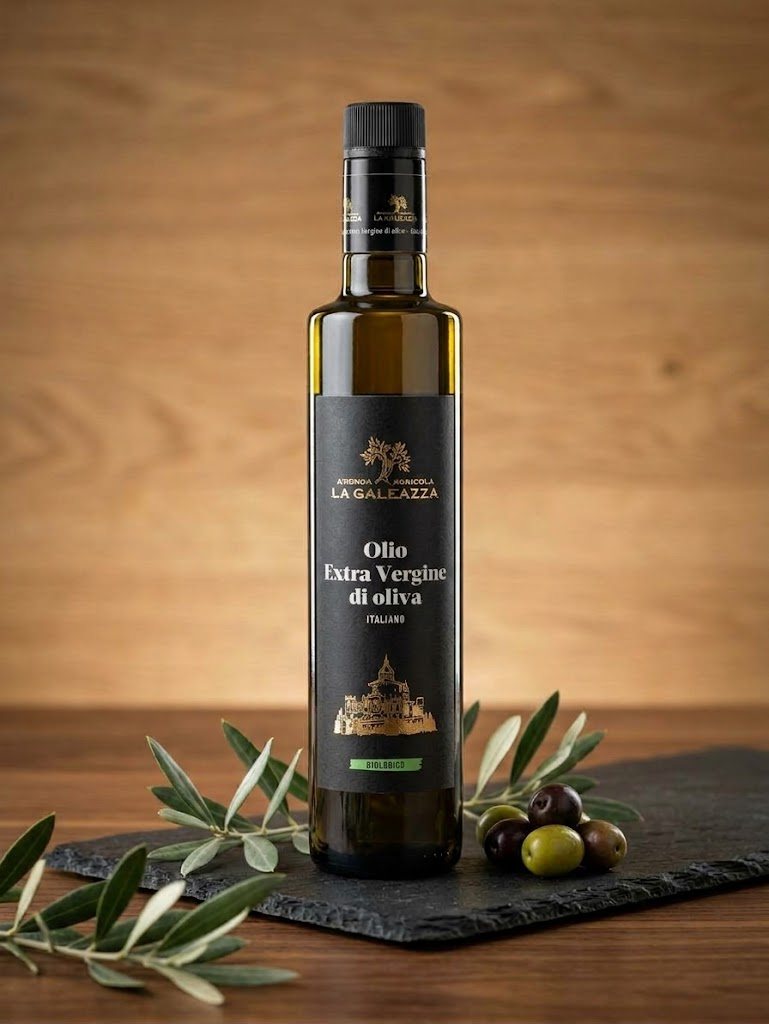 Bottiglia di olio extravergine di oliva biologico de La Galeazza su ardesia, con rametti di olivo e olive